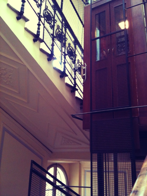 the staircase in this building has black railing and wooden door