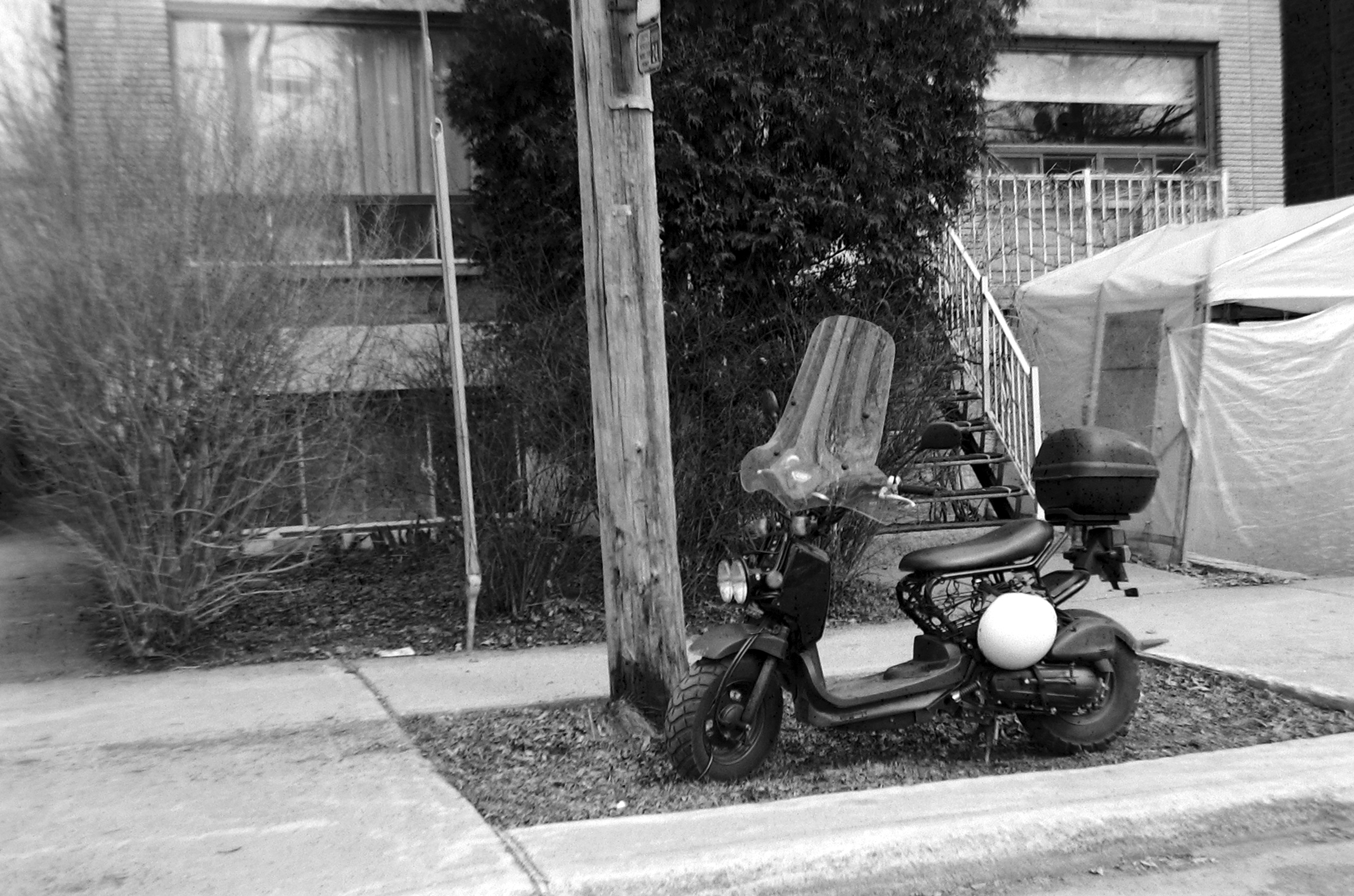 a black and white po of an older scooter parked on the curb