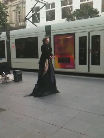 woman in long black cloak near a train
