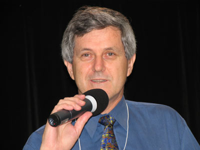 man with grey hair speaking into microphone in room