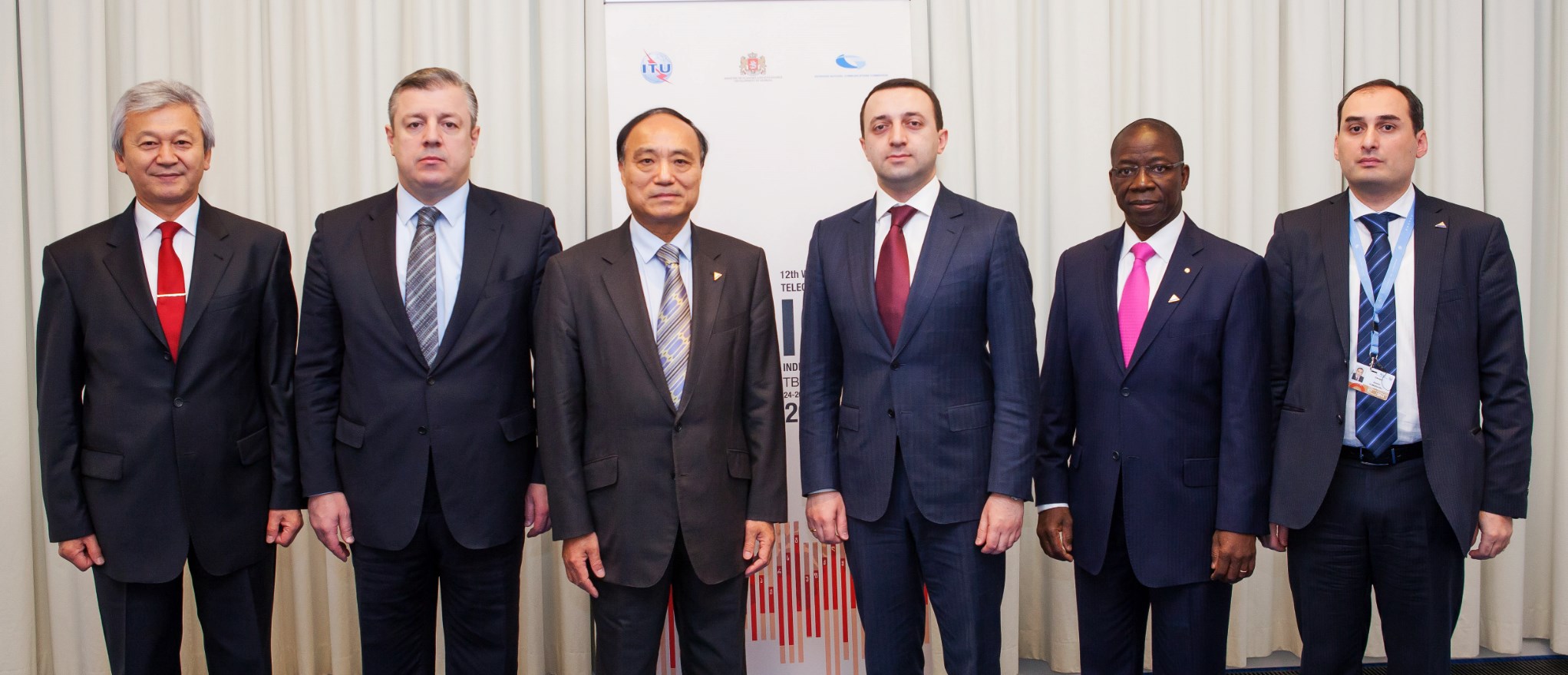 four men in business suits and ties stand near each other