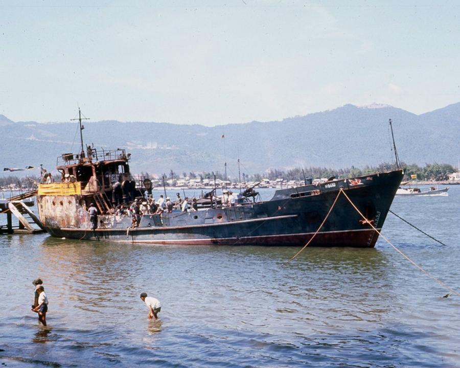 two men wading in a body of water near a ship