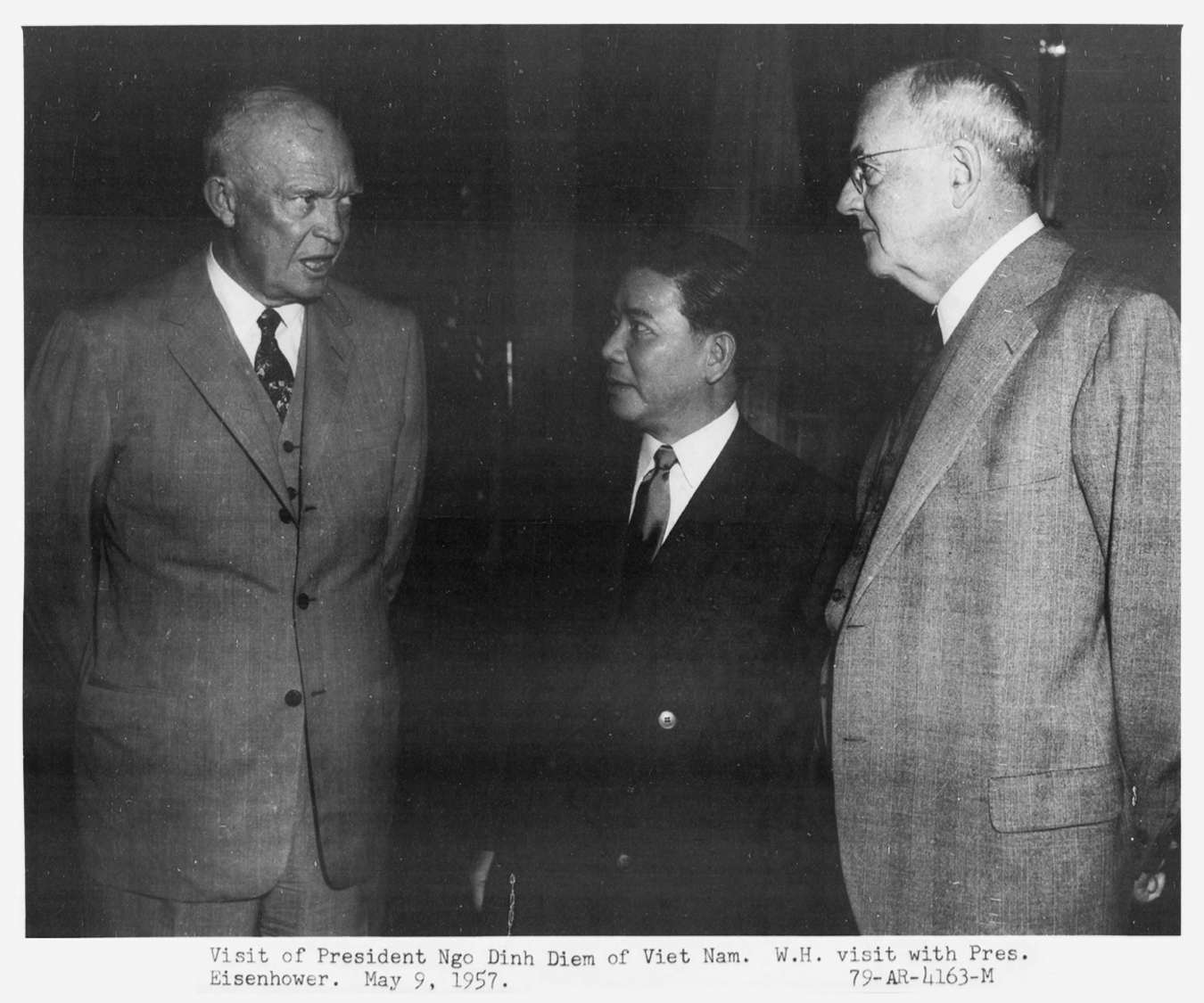 an old black and white po of two men looking at another man