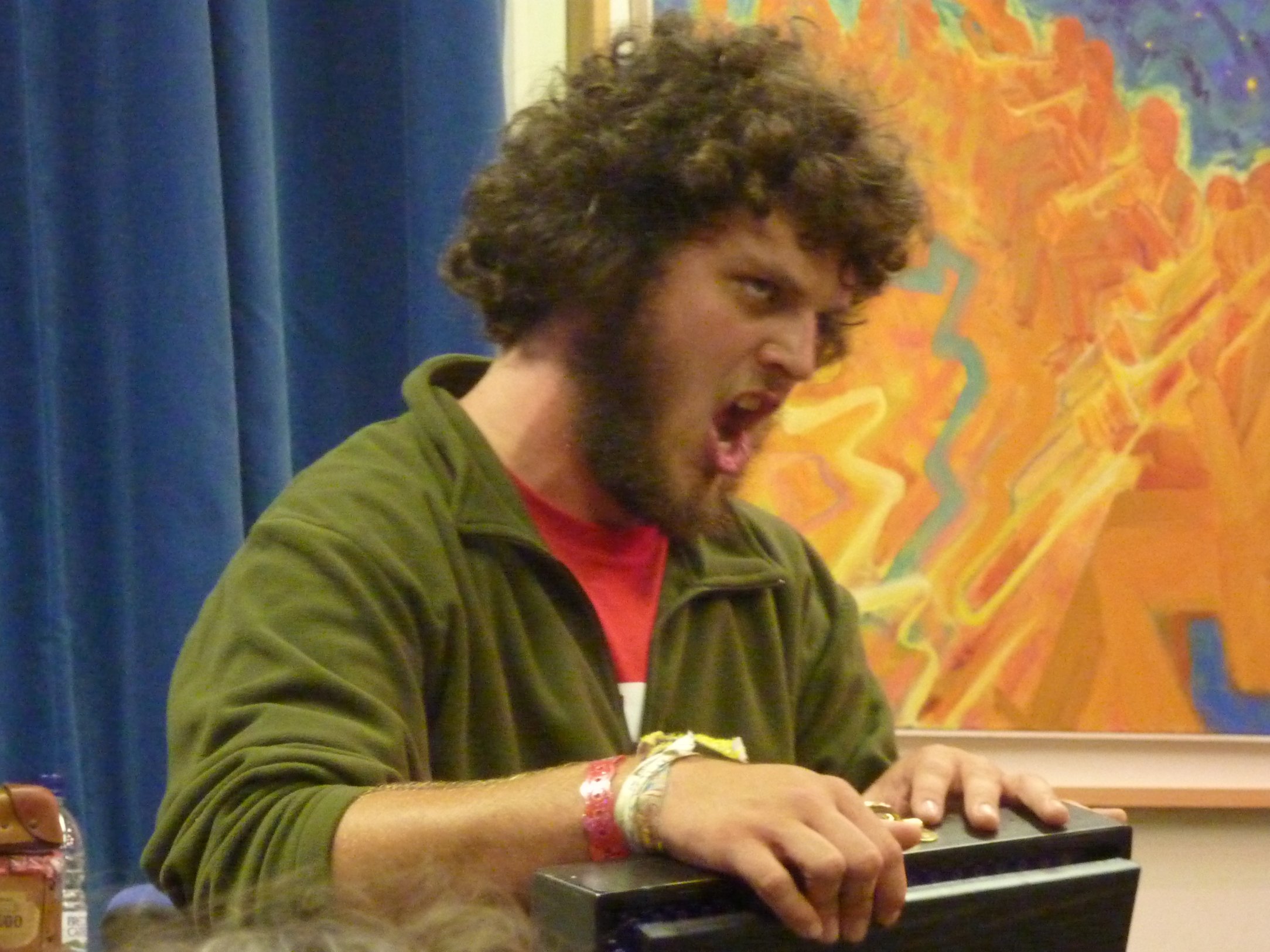 a man in an orange shirt at a desk with his mouth open