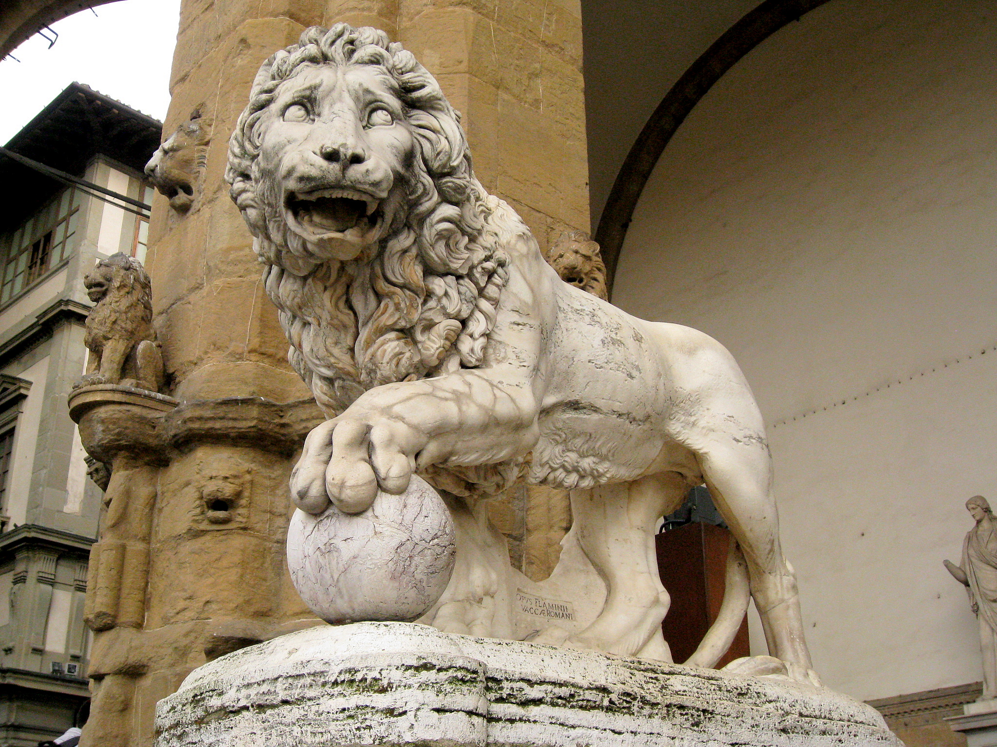 a statue of a lion holding a ball on top of it's paw