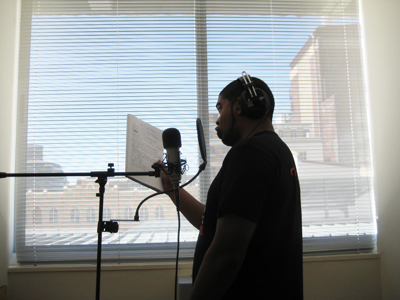 a man with headphones on stands in front of a microphone