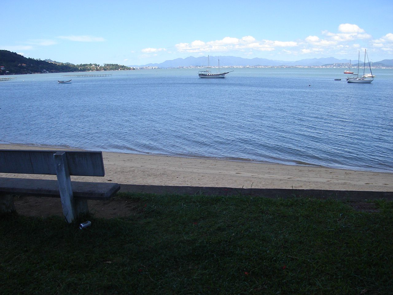 an empty bench is sitting along the edge of the water