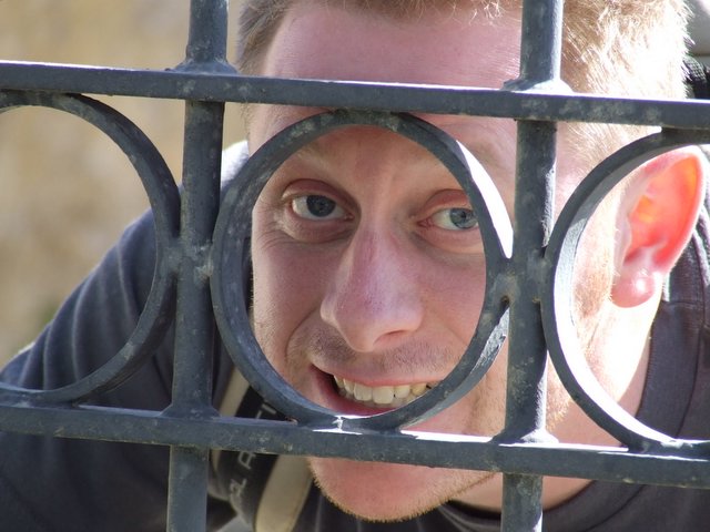 a man is standing behind a metal bars looking through it