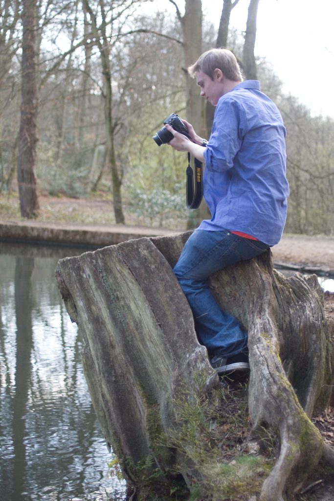 a man with a camera on a tree stump