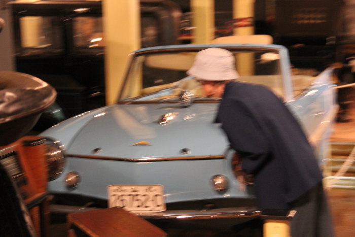 a woman in a hat is inspecting a blue car