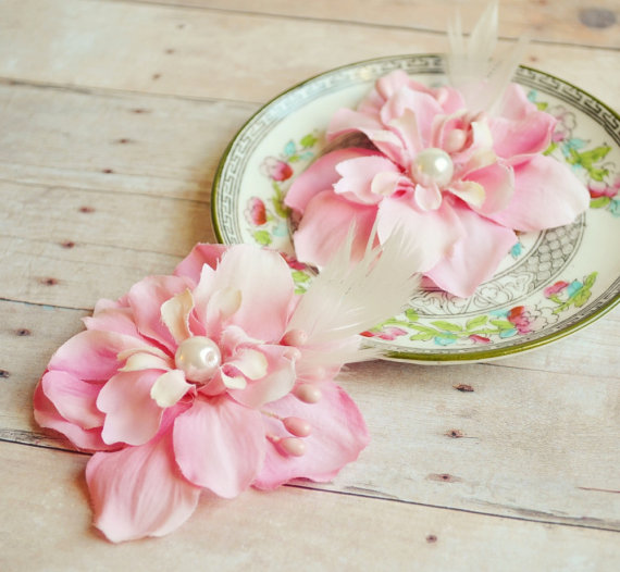 two pink flowers on a plate with feather