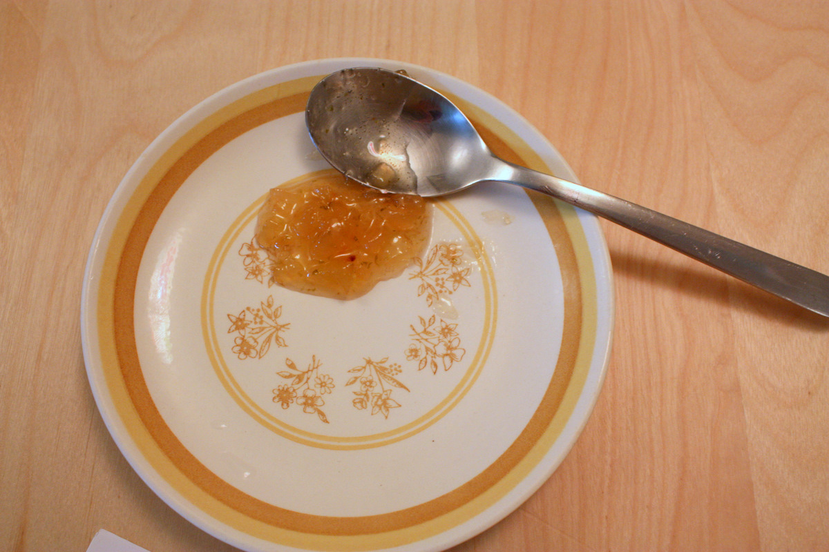 a white plate with an orange and yellow design with a spoon