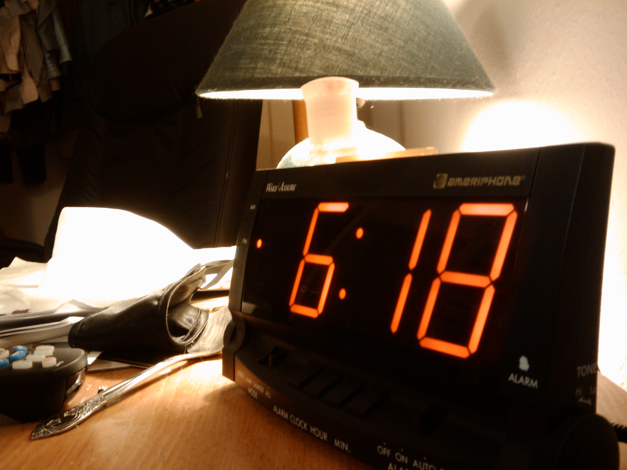 a digital clock sitting next to a lamp on top of a desk