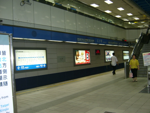 a subway train station with people waiting on the platform