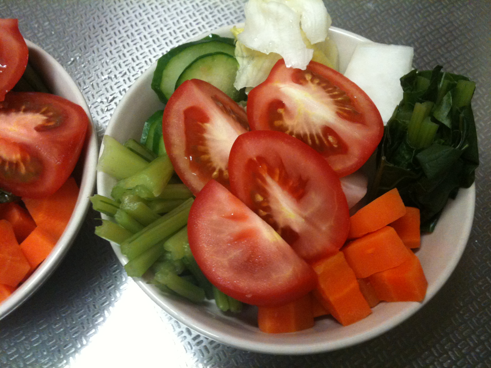 two bowls full of vegetables are arranged on a table