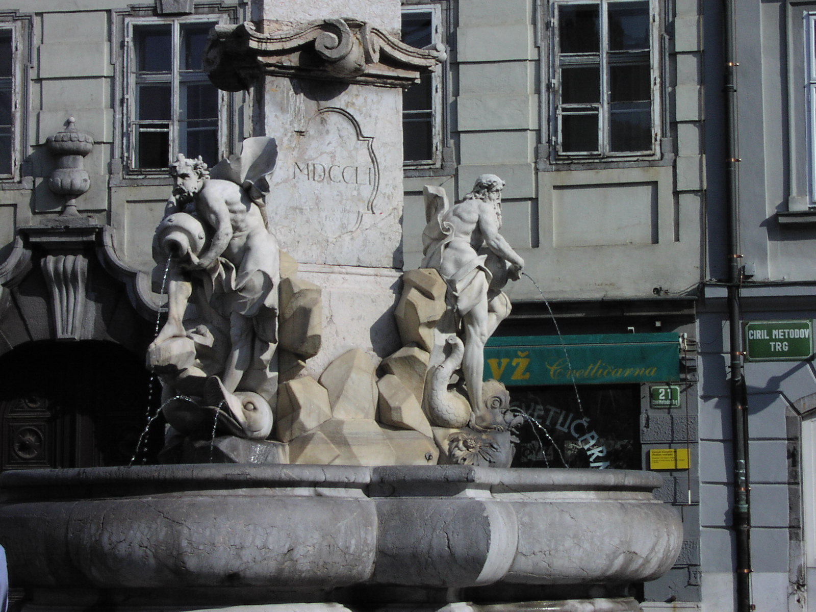 a fountain in front of a tall building near street signs