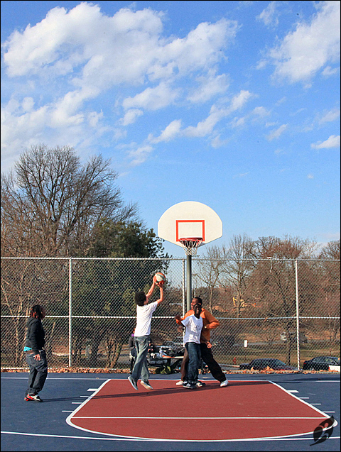 several young adults playing a game of basketball