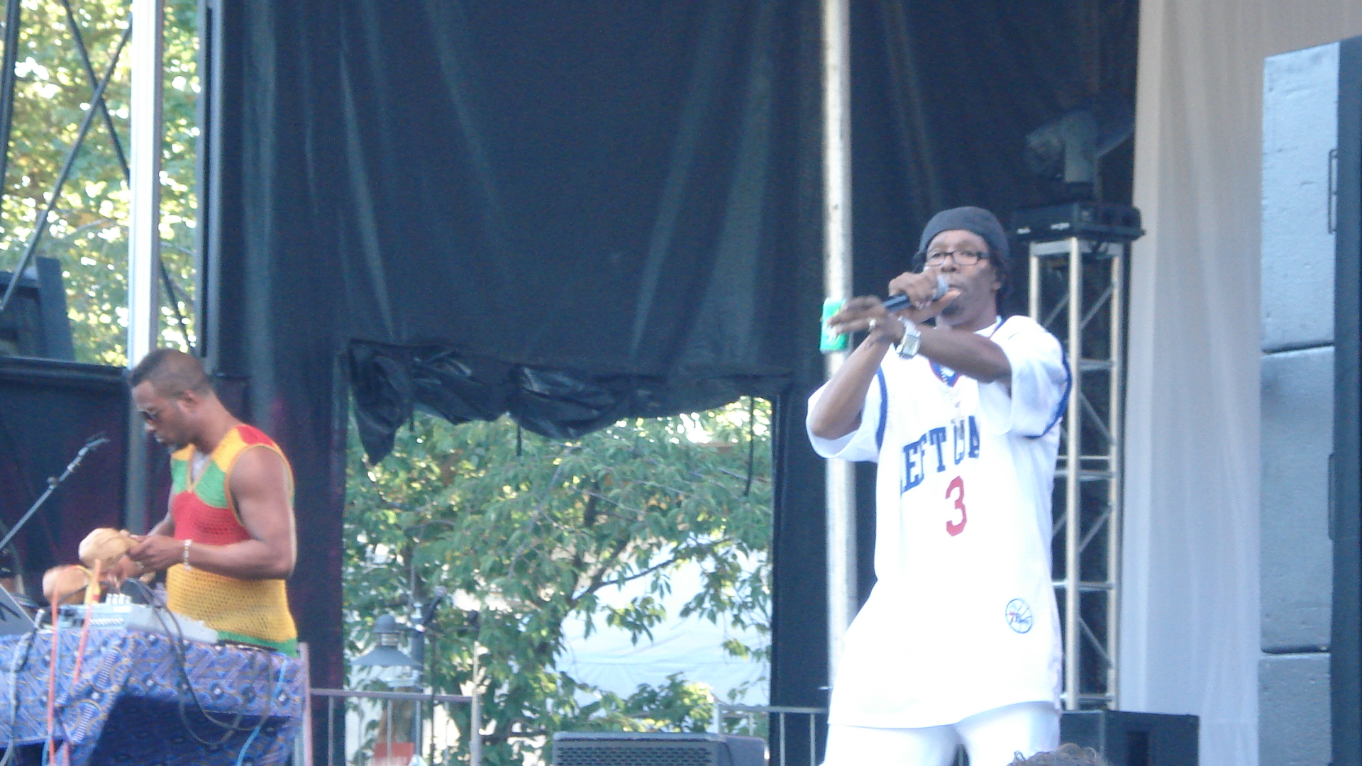 a man stands on stage and sings into a microphone as others watch