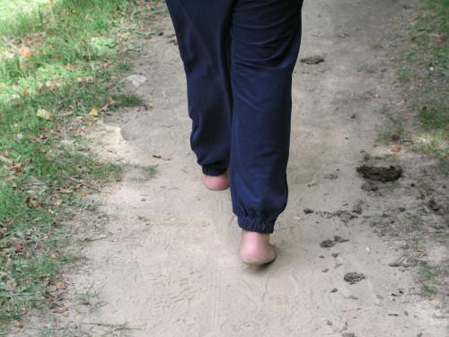 a woman with her bare foot on a path in the grass