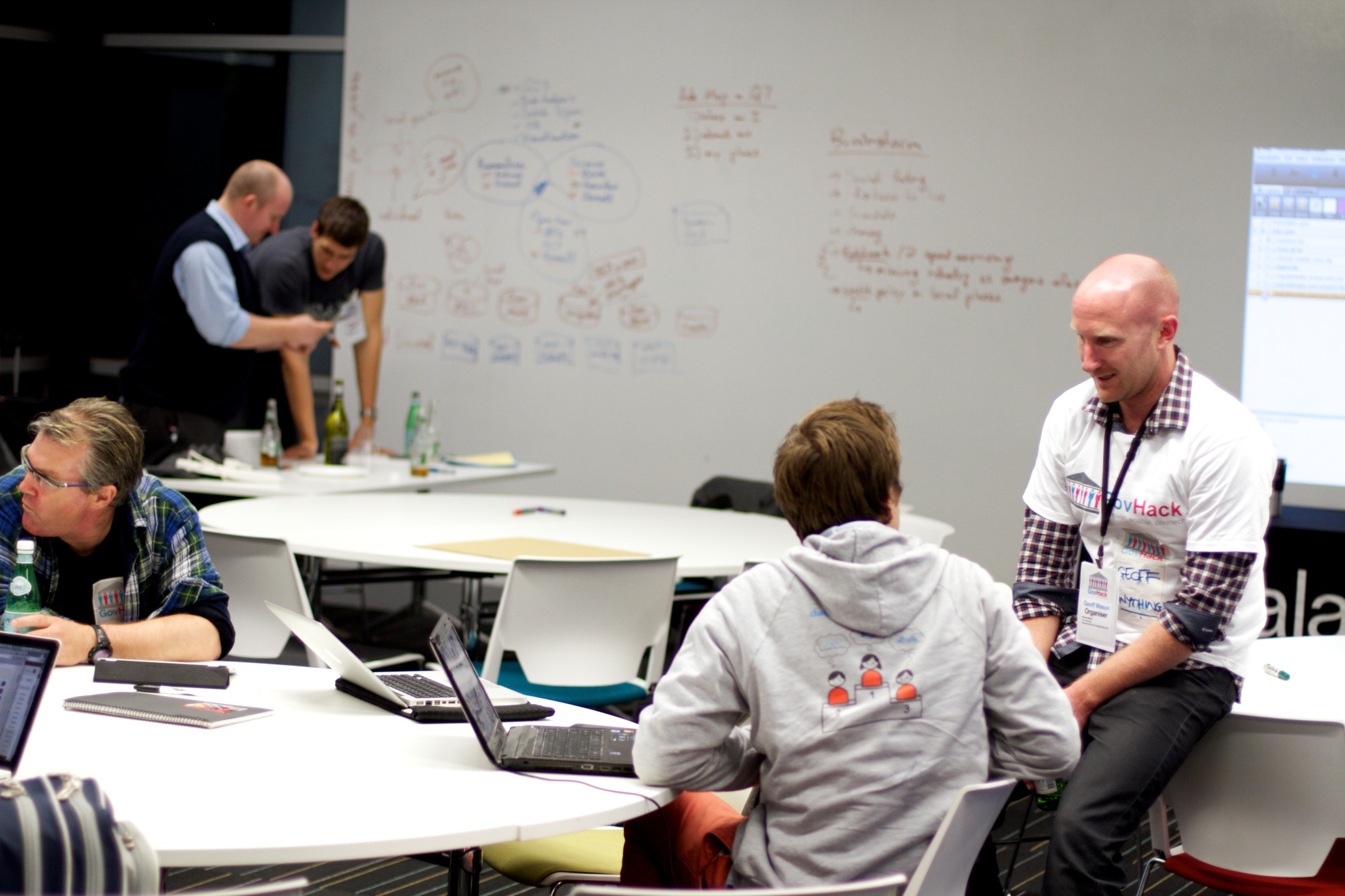 two men talk with others in a seminar