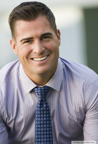 a man with a nice haircut smiling in a shirt and tie