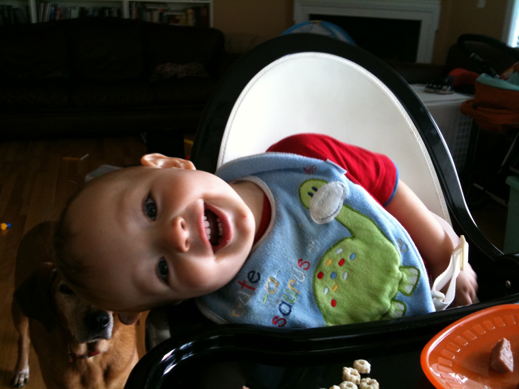 a baby in a high chair holding a food bowl with corn on it