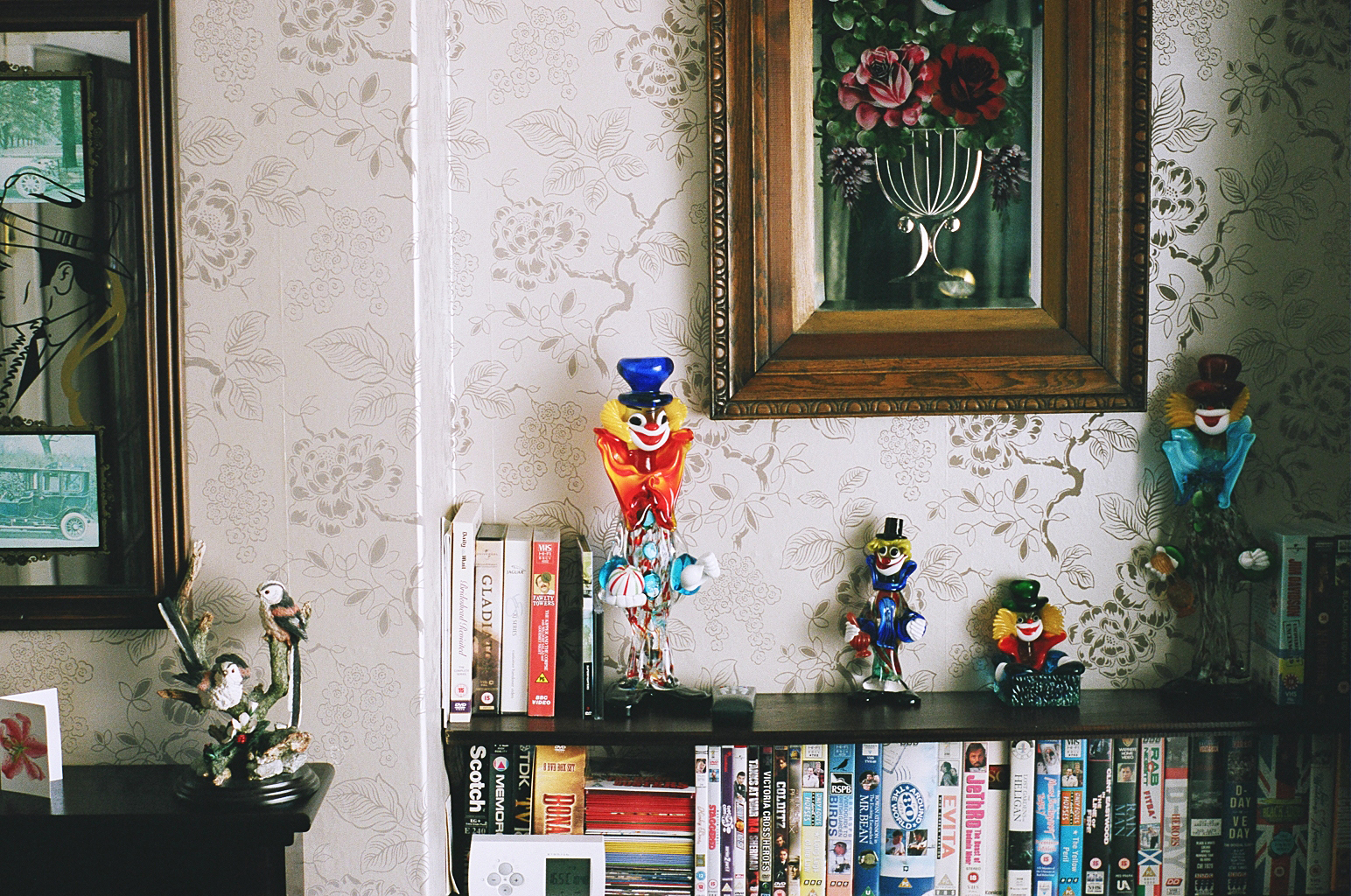 a wall mounted painting above a shelf of books