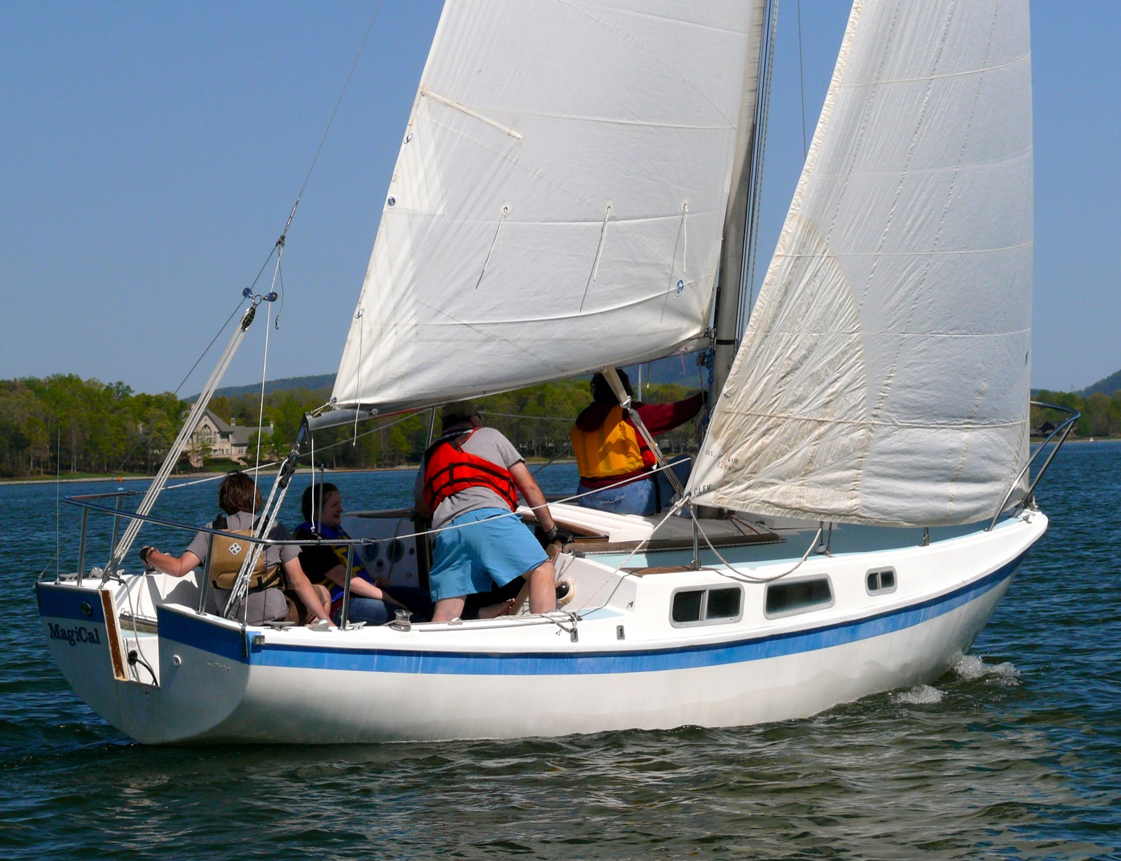 a group of people in a white sail boat on water