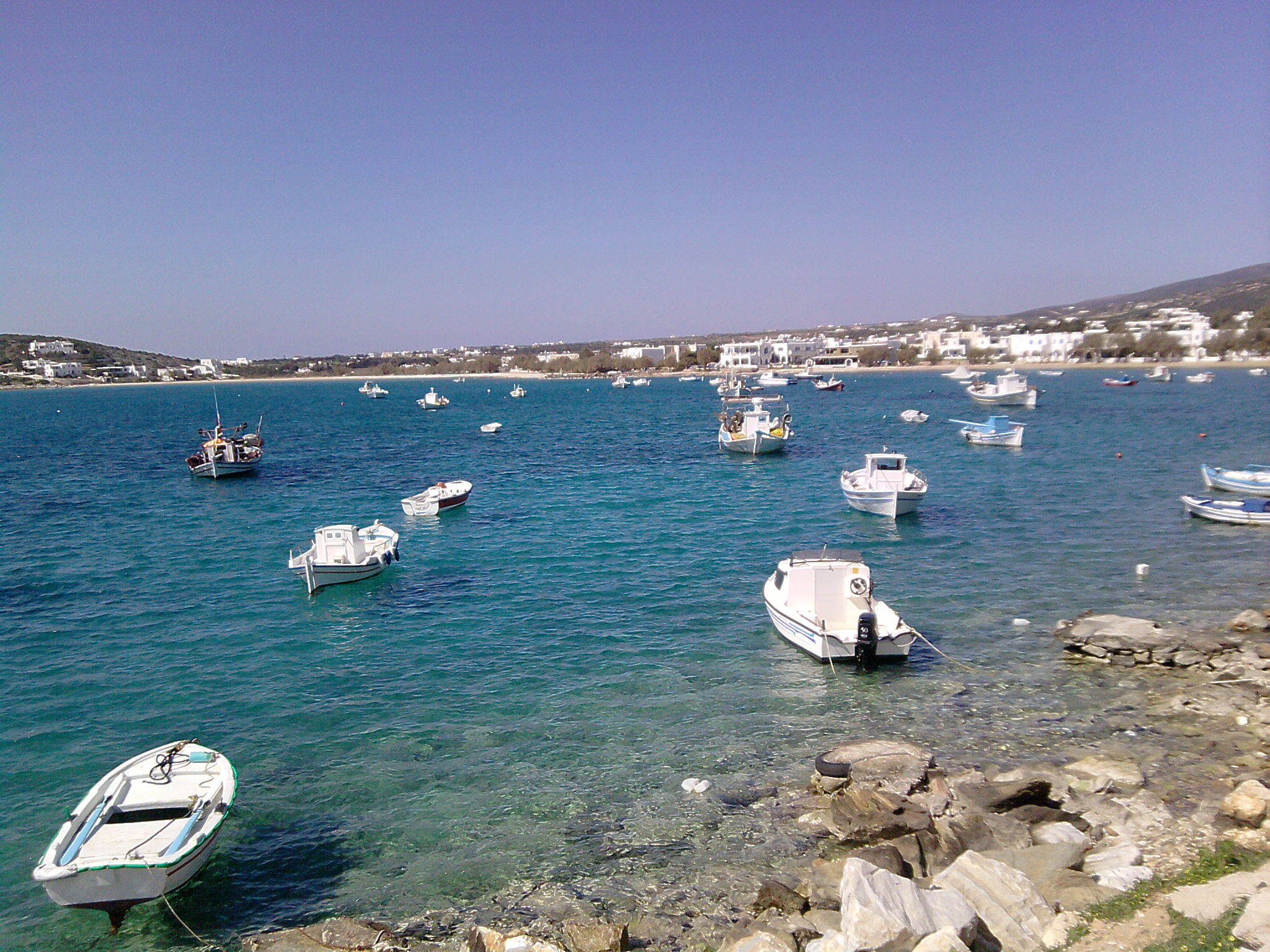 several white boats are parked on the rocks in a cove