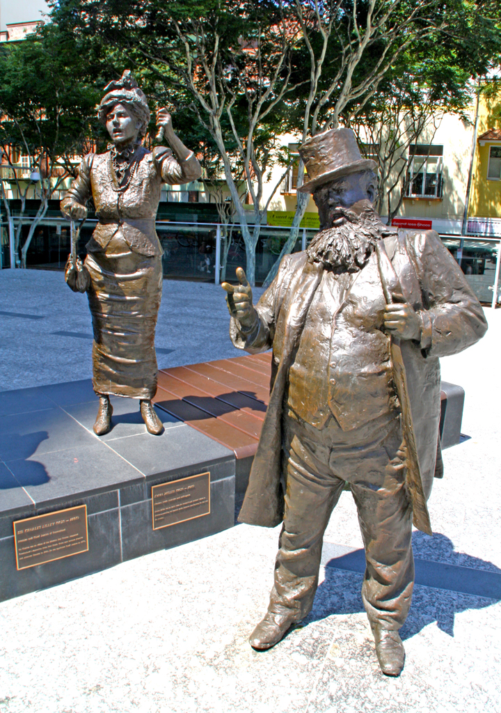 two statues of a man and a woman with hats and canes