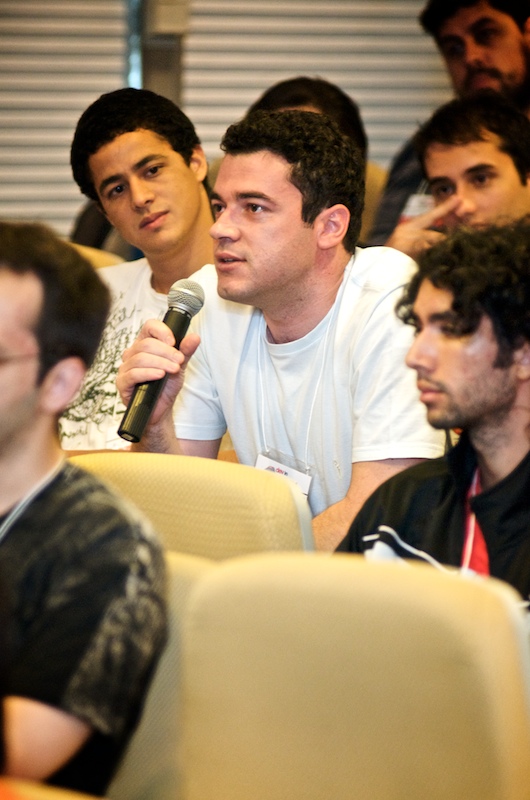 a group of people sit in rows, one man holding a microphone