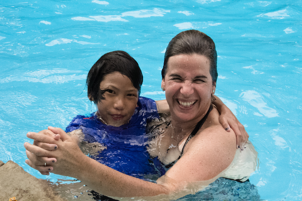 a woman and her child are swimming in the pool