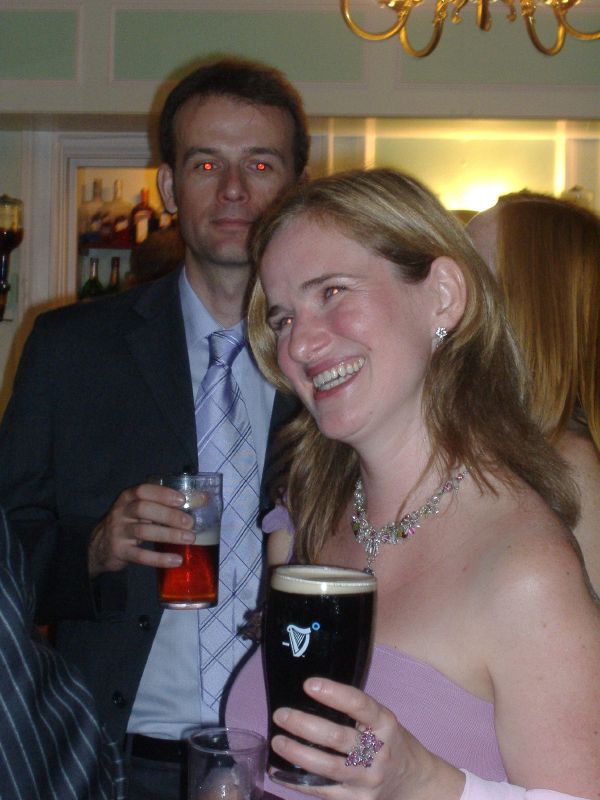two young people wearing tiaras holding glasses of beer