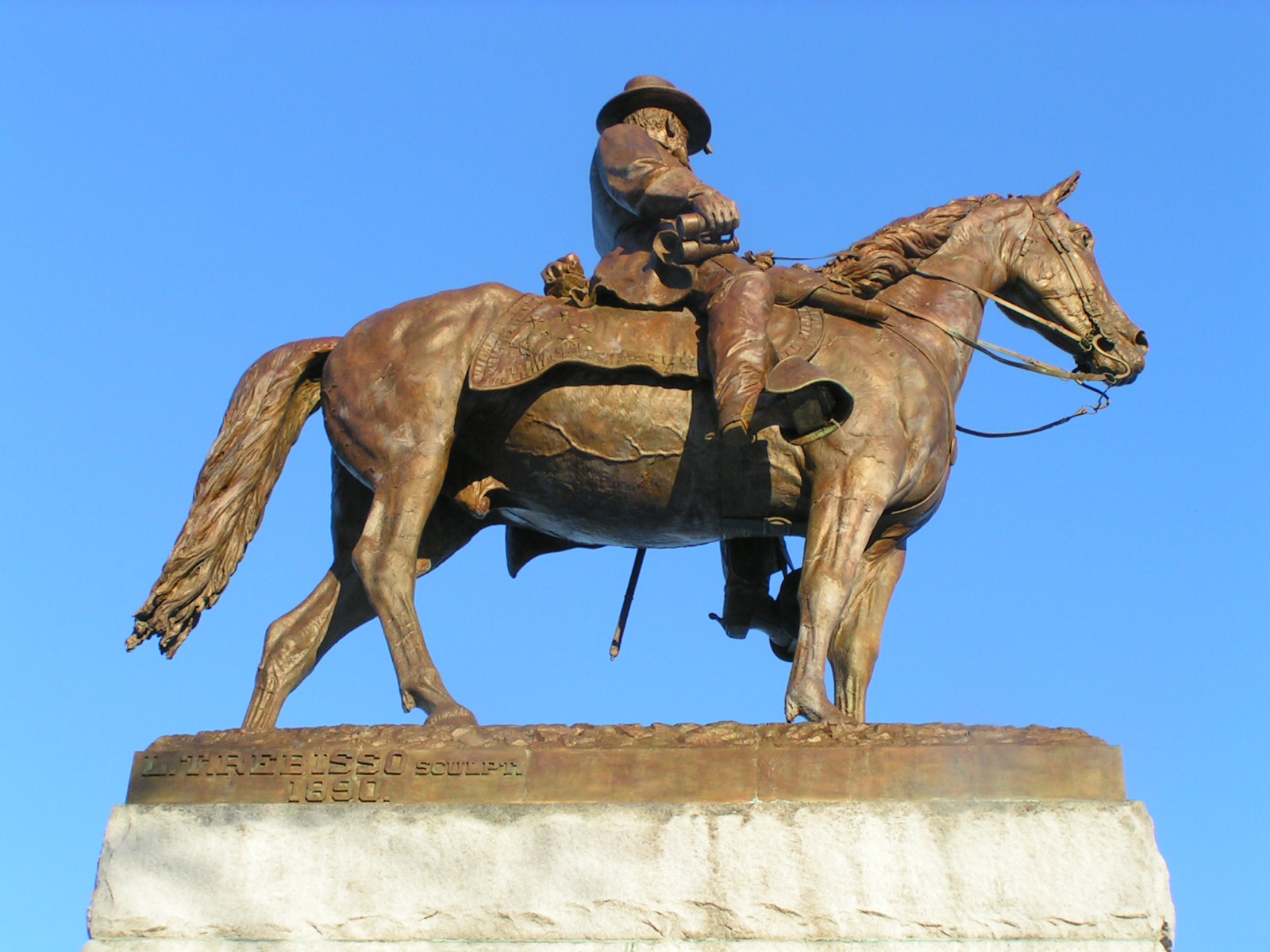 a man in western gear sitting on a horse statue