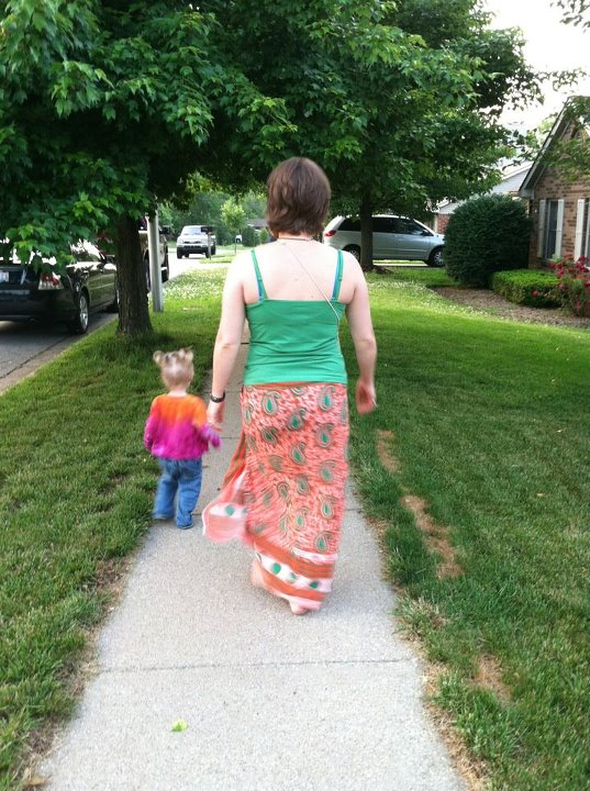 a woman is walking next to her child on the sidewalk