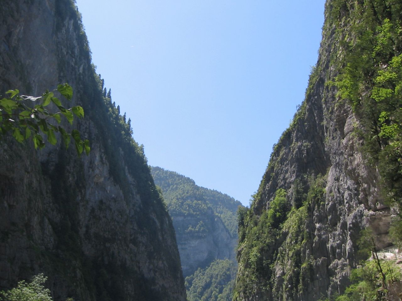 some people are rafting in the water by mountains