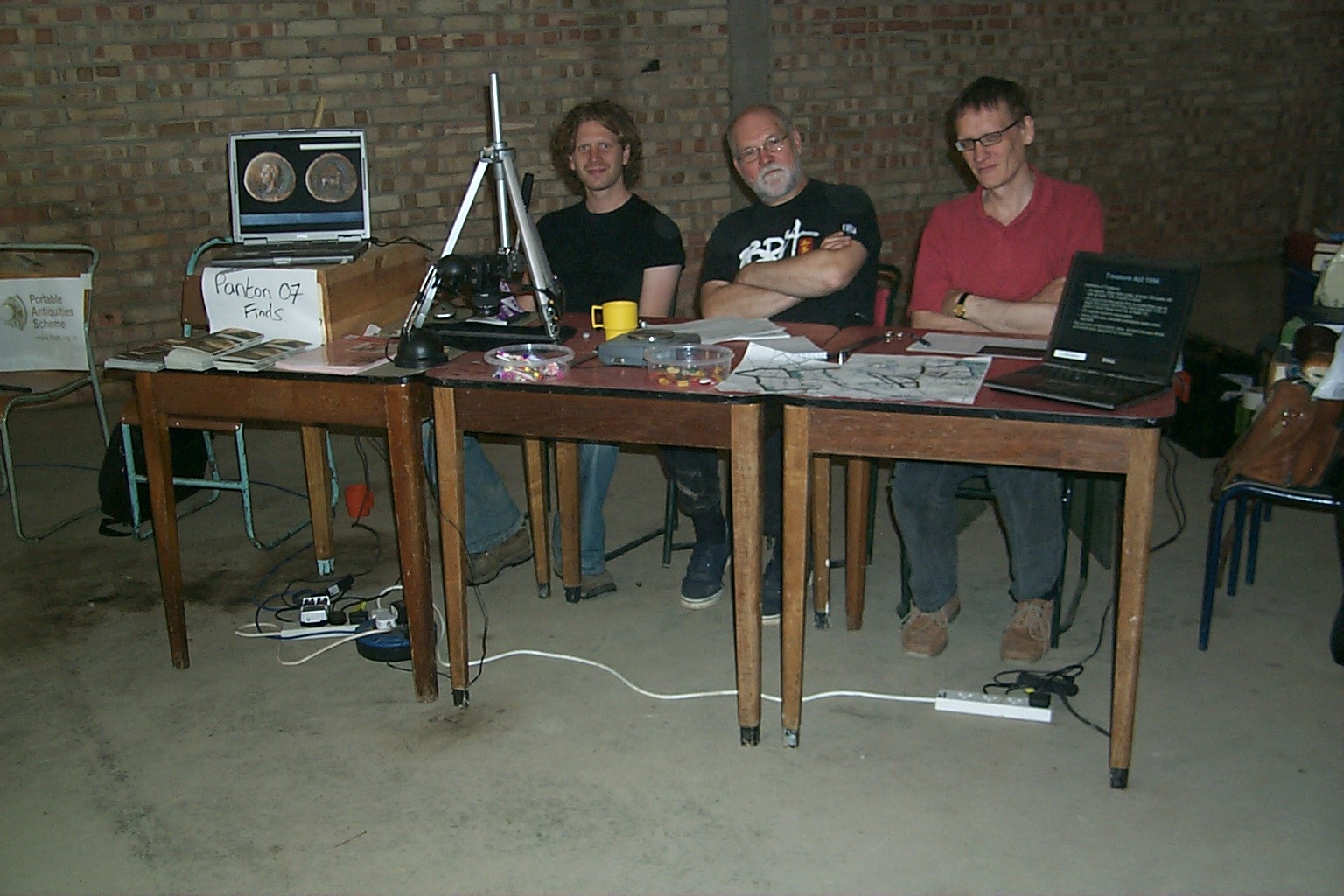 three guys sitting at a table in a workshop