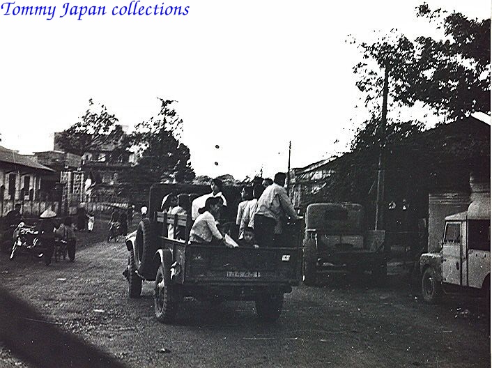 a vintage pograph of men loading items in the back of a pickup truck