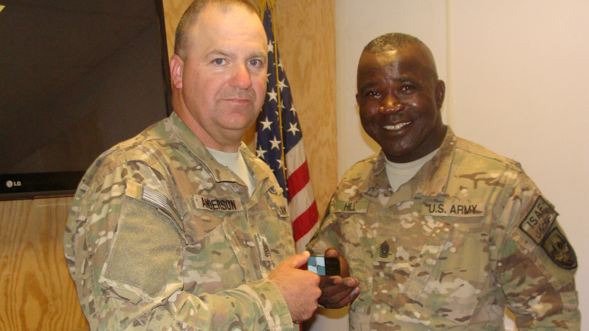 a man in military attire smiling and holding a smart phone