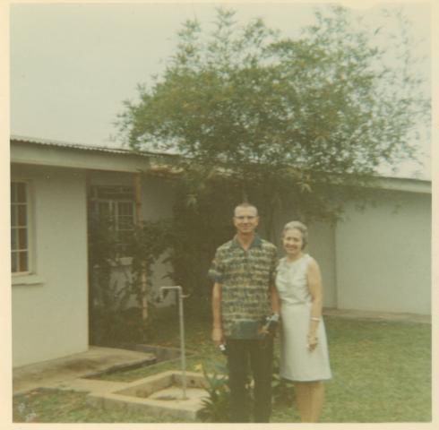 a couple in front of a house posing for a picture