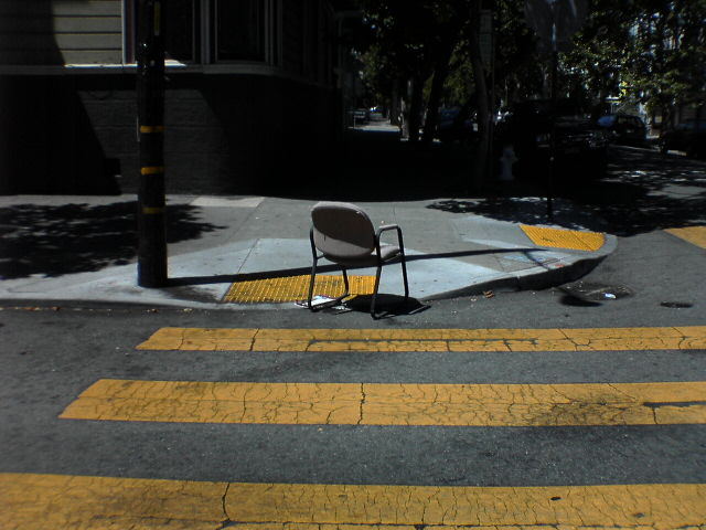 a broken chair sitting in the middle of the road