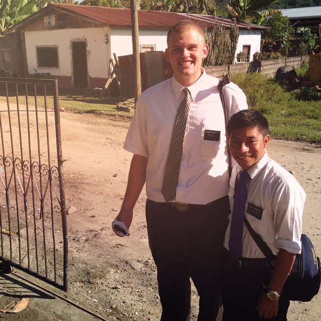 two boys standing beside each other by the fence