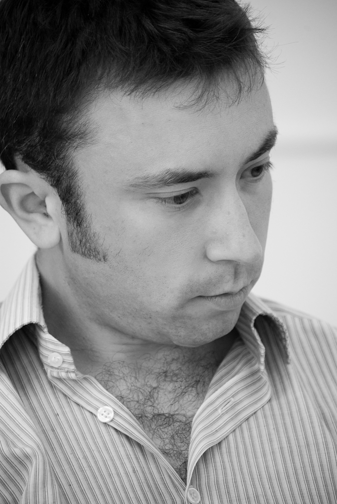 a man looking down while wearing a striped shirt
