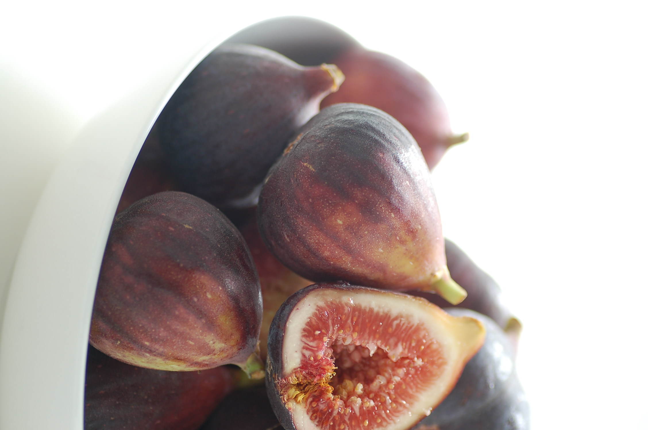 a white bowl of figs is sitting on the table