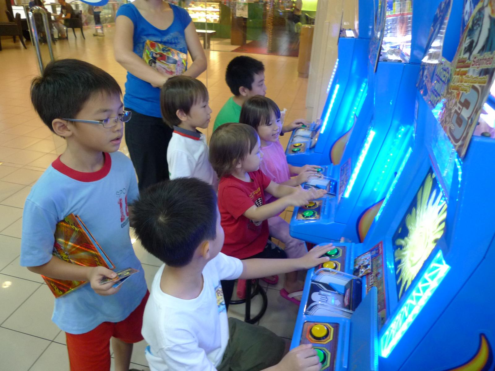 children play a video game in a mall lobby
