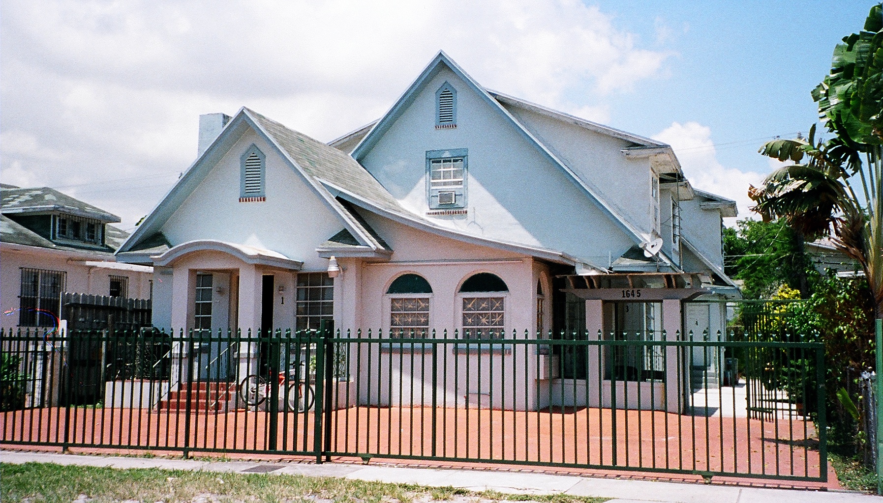 a large pink house with large windows and a fence