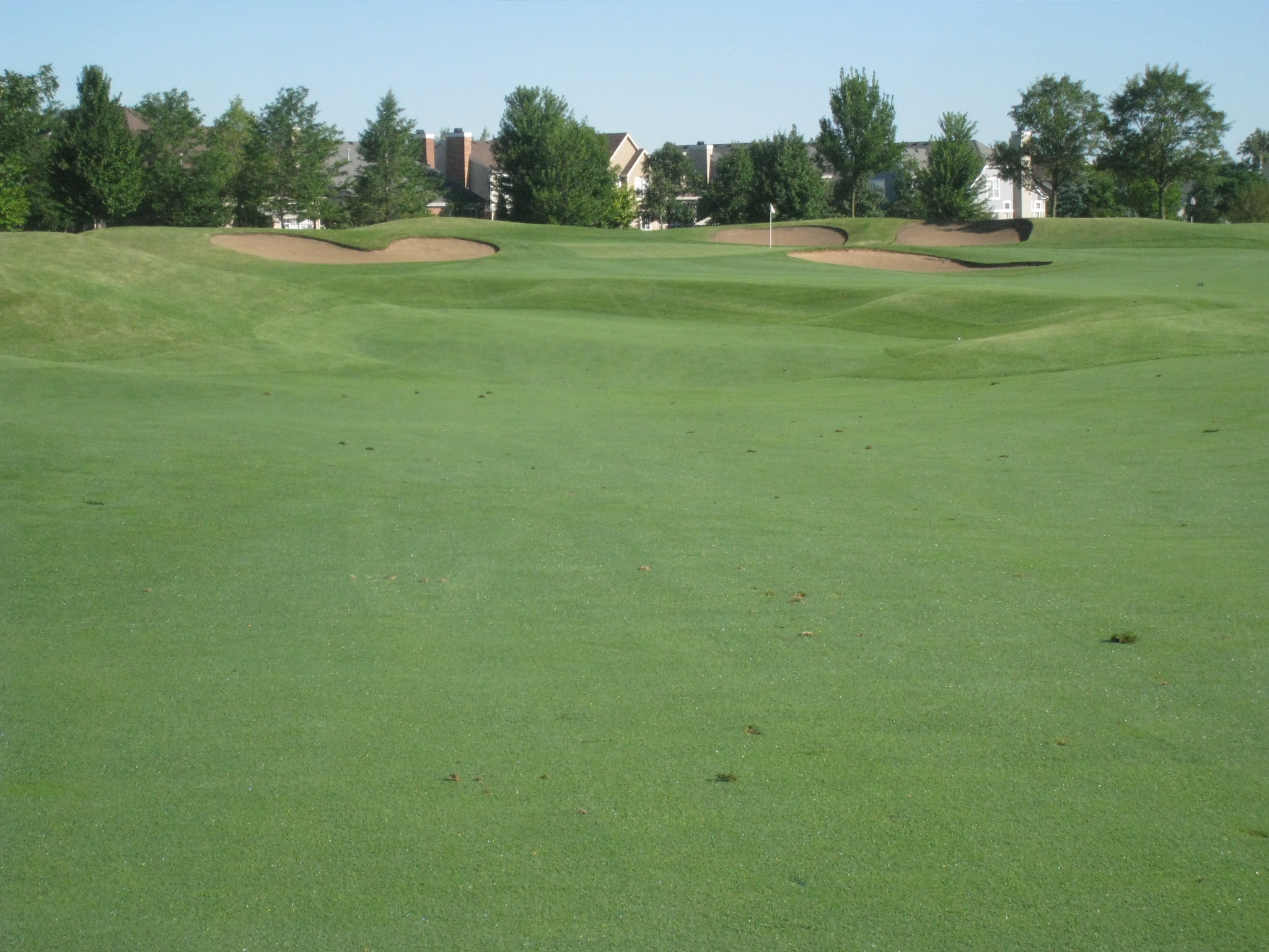 the golf course has grass and houses in the background