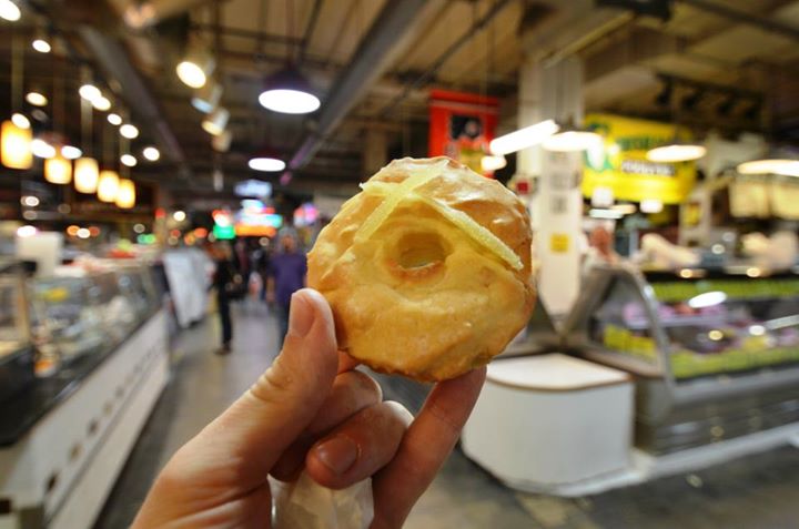 a doughnut in a donut shop with people walking past