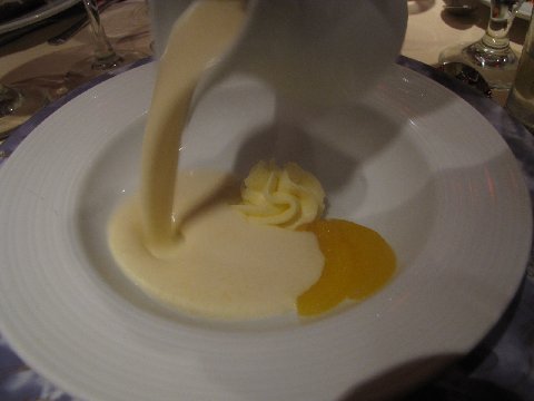 a glass bowl filled with food and a white sauce being poured on it