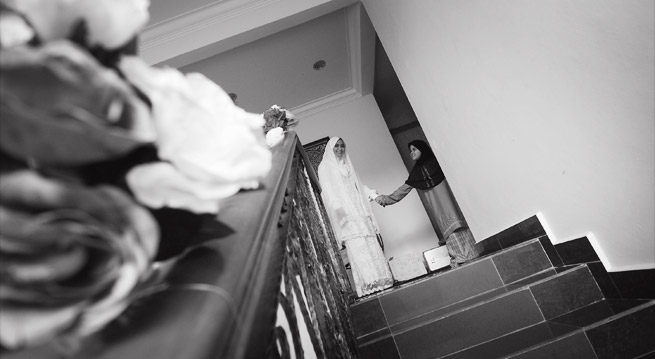 a bride descends a stairway from her wedding dress